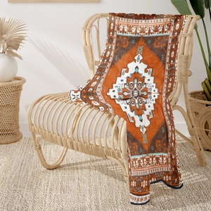 Detail of bohemian patterned throw blanket with turquoise accents on a rattan chair
