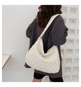 Detail of white quilted tote bag in soft nylon fabric worn by a model against a white wall
