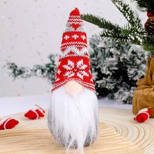 Christmas gnome doll with red snowflake knit hat and long white beard on festive background