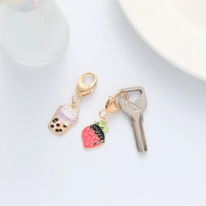 Detailed view of enamel cat charms in milk tea and strawberry shapes with heart clasps