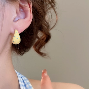 Close-up of yellow water drop earrings with blue polka dots on a female model