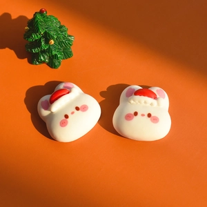 Close-up of DIY resin white rabbit charms with Santa hats for Christmas craft accessories