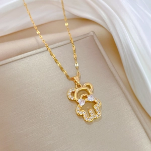 Detailed macro view of a gold teddy bear pendant with sparkling zircon bowknot detail
