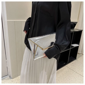 Detail of silver envelope clutch bag with crocodile texture and gold metal trim