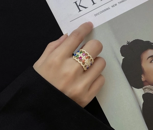 Close-up of wide 18k gold plated openwork ring featuring colorful baguette zircons