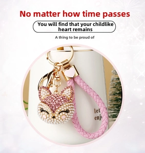 Detailed view of pink fox keychain with rhinestones, pearls, and braided strap on a cup