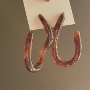 Detailed shot of brown resin hoop earrings with amber texture on a display card