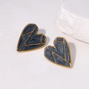 Macro shot of 18K gold plated heart stud earrings with dark grey star texture finish