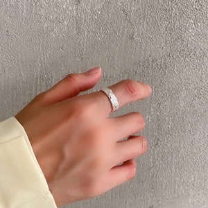 Macro detail of silver wide ring with hammered texture and minimalist style worn on finger
