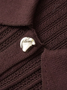 Dettaglio di un bottone metallico argento su tessuto a maglia marrone scuro