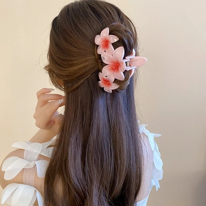 Detail of pink acrylic floral hair claw clip on model showing delicate gradient petals