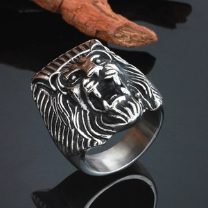 Relief détaillé d'une bague tête de lion argentée sur bois sombre et socle de miroir noir