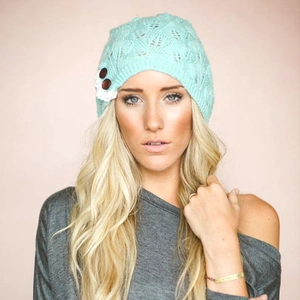 Detailed view of mint green knit beanie with hollow leaf pattern and lace button trim