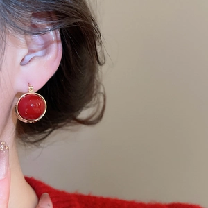 Detail side view of vintage red zircon earring with golden rim on model ear
