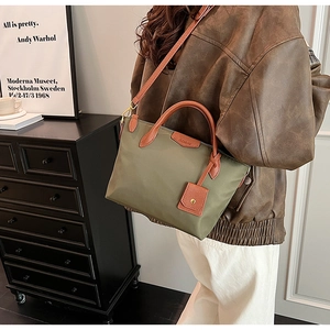 Detailed shot of dark green nylon tote with brown leather trim and Clarux logo