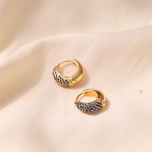 Macro shot of 18K gold plated earrings featuring sparkling blue cubic zirconia stones