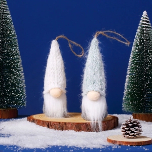 Close-up of white and light blue Christmas gnomes on wood slice with snowy background