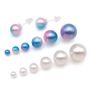 Detail view of colorful gradient and white pearl stud earrings in various sizes on white background
