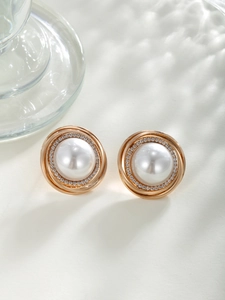 Detail of vintage round pearl earrings with gold metal rings and zircon accents