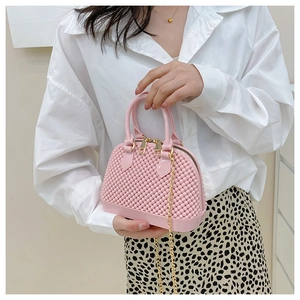 Detail of pink PVC jelly bag with granular texture and golden chain strap for girls