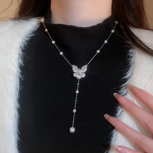 Dettaglio macro della collana a farfalla in argento con zirconi pavé e perle bianche a Y