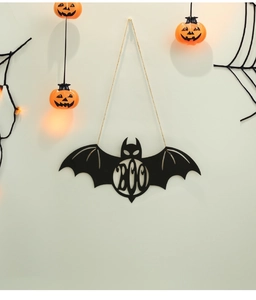 Detail view of black bat BOO door sign hanging on a white wall with pumpkin decor