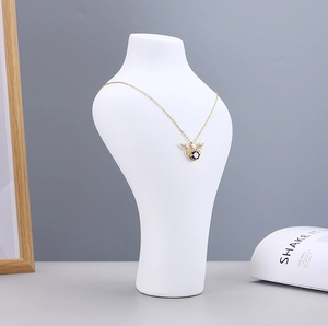 Detail of gold necklace with deer antler pendant and purple stone on white bust mannequin