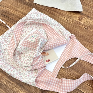 Close-up of floral and plaid patchwork tote bag with brand label on a wooden desk