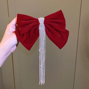 Detail of red velvet bow hair clip featuring elegant long silver rhinestone tassels
