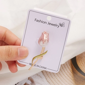 Detail of pink tulip brooch with enamel finish and gold leaves on a display card