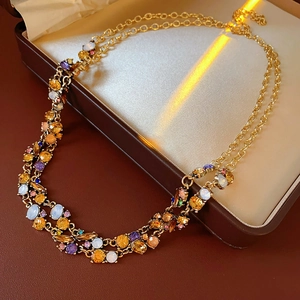 Detail of a vintage double-layer gold necklace with multi-colored crystals on a jewelry box