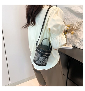 Rear view of a model carrying a black cylinder bucket bag with silver embroidery