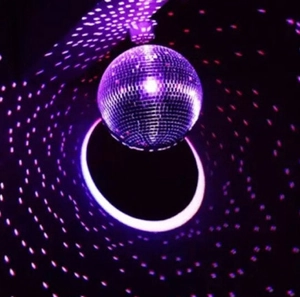 Macro shot of mirror disco ball reflecting vibrant purple radial light spots in dark party setting