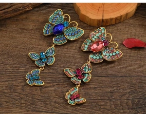 Close-up of vintage butterfly pins with colorful rhinestones on a rustic wooden background