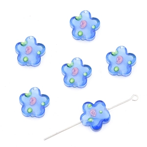 Blue glass flower beads for DIY jewelry making with a metal needle on white background