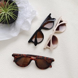 Retro round frame sunglasses in black, cream, and tortoise colors with dark lenses