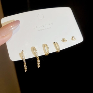 Detail of 3-pair gold earring set with zircon triangles and delicate tassel hoops