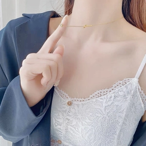 Minimalist gold cross necklace with crystal pendant shown on model's neckline