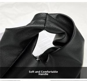Close-up of black lychee-textured faux leather handbag with soft knotted handle detail