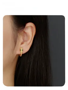Detailed close-up of a golden snake head earring with green gemstone eyes on model