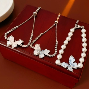 Vue détaillée de bracelets papillon avec cristaux et perles sur un coffret à bijoux rouge