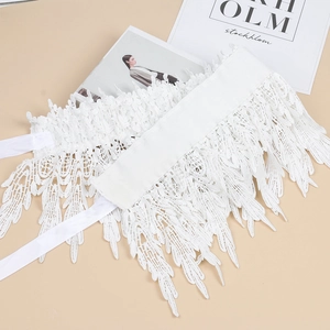 Detail view of intricate white lace embroidery with floral patterns and ribbon ties