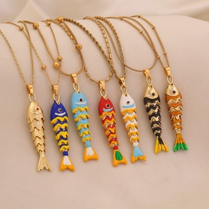Colorful enamel fish pendant necklaces in gold finish displayed on soft fabric