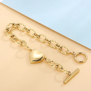 Détail de la gourmette en acier doré 18k avec fermoir à bascule OT et pendentif en cœur