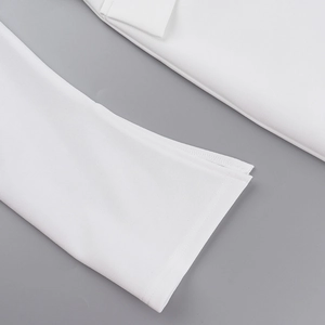 Détail du poignet fendu et des coutures précises sur cette robe blanche élégante d'automne