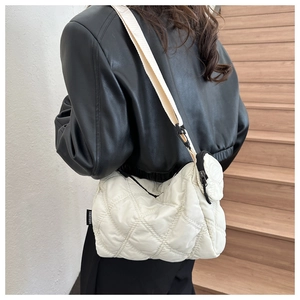 Détail d'un sac à bandoulière matelassé crème avec étiquette et sangle réglable