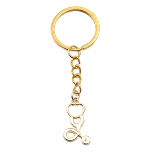 Detail view of a gold metal stethoscope keychain pendant with white enamel filling
