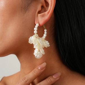 Créoles dorées élégantes avec perles blanches et pendentifs pétales translucides sur mannequin