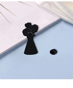 Detail view of the black metal pin back and butterfly clutch closure on white surface
