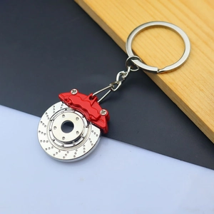 Detail of silver brake disc keychain with red caliper showing metal texture and alloy finish